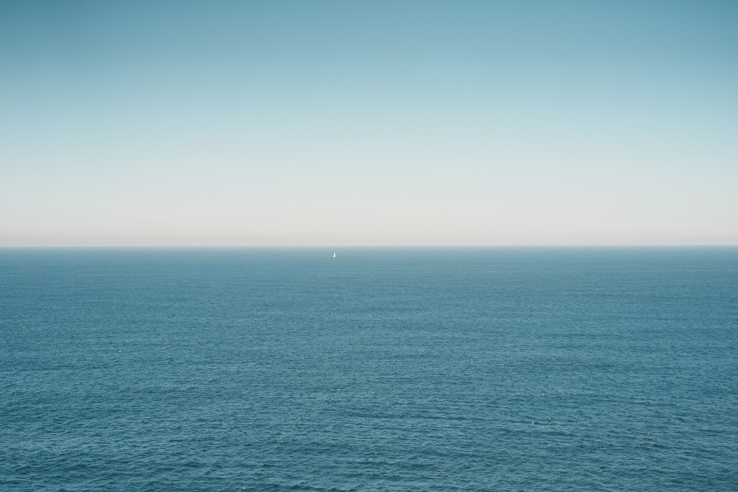 A lone sailboat on a wide blue sea